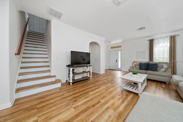 living room featuring visible vents, arched walkways, stairs, and hardwood / wood-style flooring