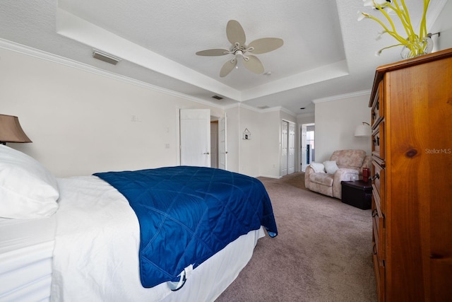 carpeted bedroom featuring visible vents, a textured ceiling, a tray ceiling, and ornamental molding