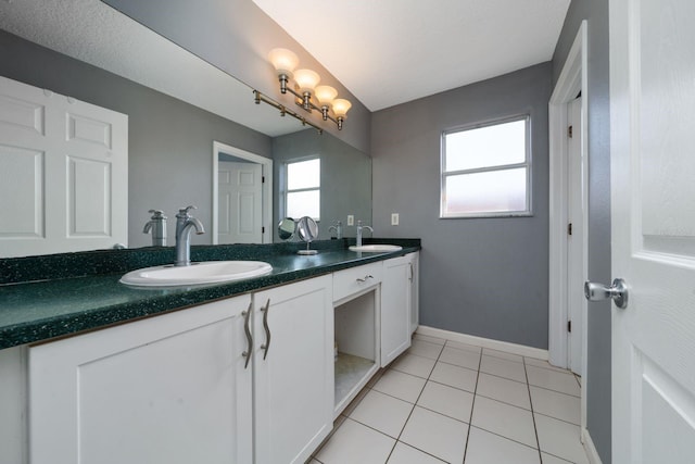 full bath featuring tile patterned flooring, double vanity, baseboards, and a sink