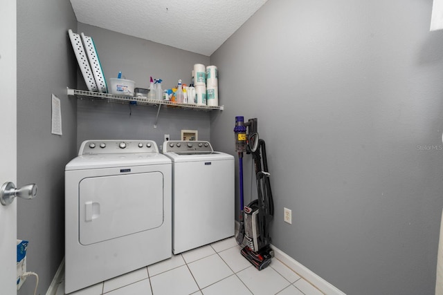 laundry room featuring independent washer and dryer, a textured ceiling, light tile patterned floors, baseboards, and laundry area