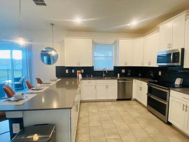 kitchen featuring a sink, dark countertops, stainless steel appliances, a peninsula, and decorative backsplash