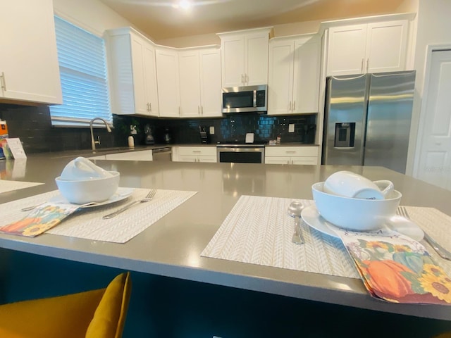 kitchen with white cabinets, backsplash, appliances with stainless steel finishes, and a sink