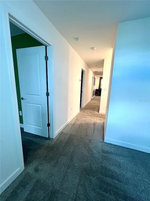 corridor with baseboards and carpet