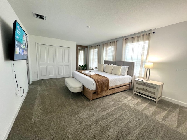 bedroom with visible vents, baseboards, carpet, a closet, and a textured ceiling