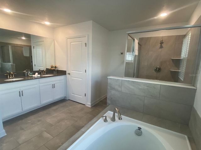 bathroom featuring double vanity, a stall shower, a bathtub, and a sink