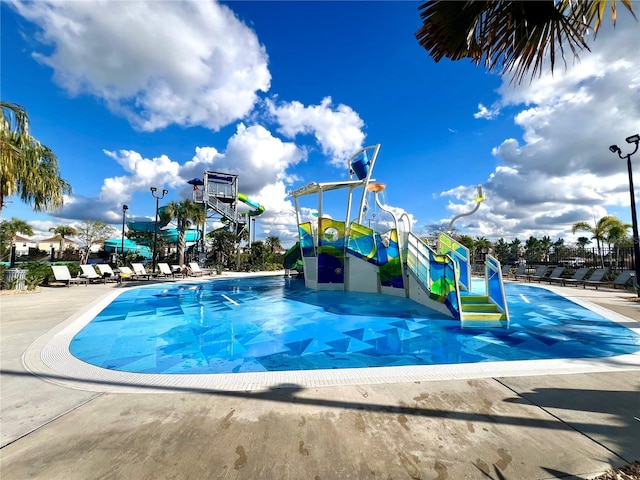 pool with playground community, a water slide, and a water play area