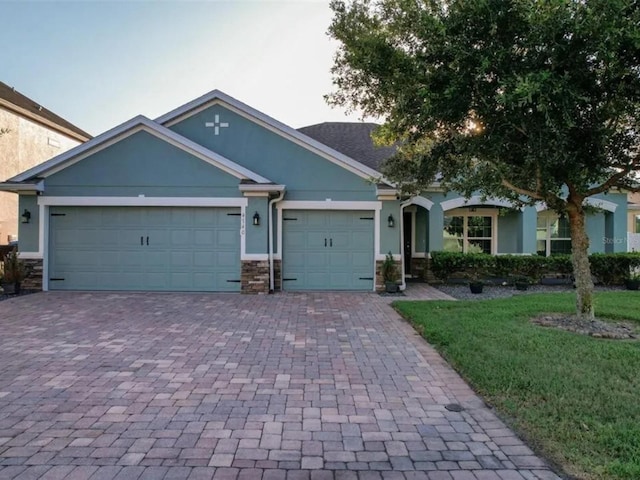 view of front facade featuring stucco siding, decorative driveway, stone siding, a front yard, and an attached garage