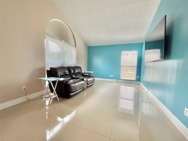 living area with baseboards, a textured ceiling, lofted ceiling, and tile patterned flooring