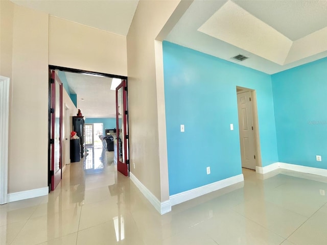 empty room featuring light tile patterned flooring, visible vents, and baseboards