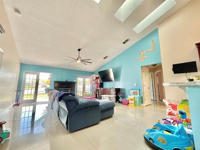 living room with visible vents, light tile patterned floors, a skylight, a textured ceiling, and a ceiling fan