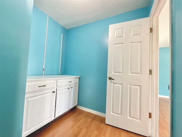 bathroom featuring a textured ceiling, baseboards, and wood finished floors