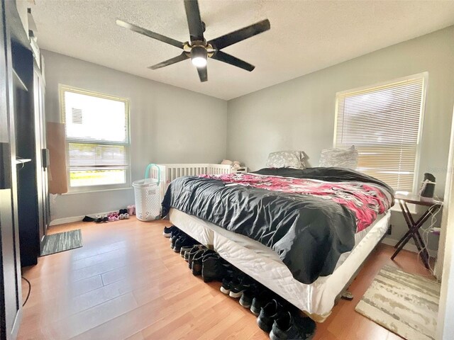 bedroom with ceiling fan, wood finished floors, and a textured ceiling