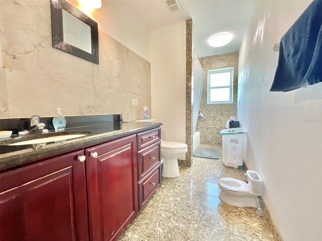 full bath featuring vanity, visible vents, a walk in shower, tile walls, and toilet