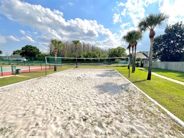 surrounding community featuring a tennis court, a yard, fence, and volleyball court