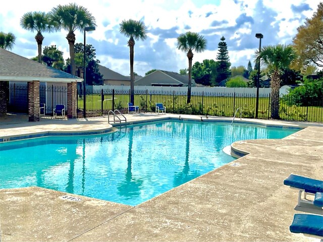 pool with a patio area and fence