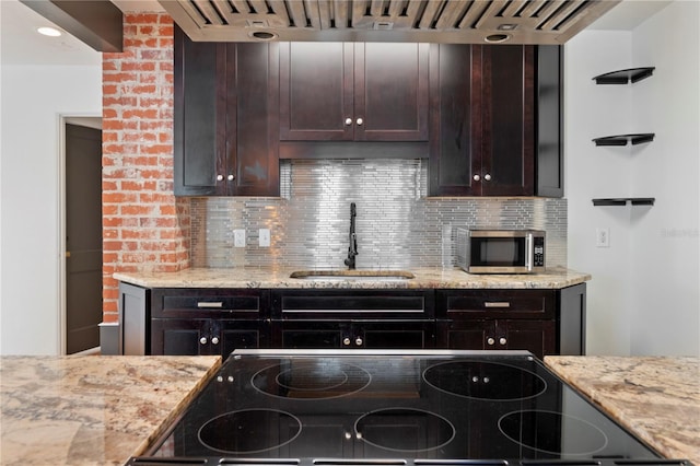 kitchen featuring electric stove, a sink, stainless steel microwave, decorative backsplash, and light stone countertops