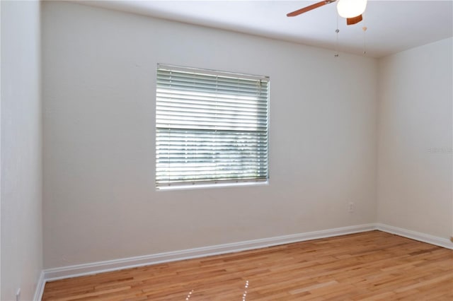 spare room featuring a ceiling fan, light wood-style floors, and baseboards