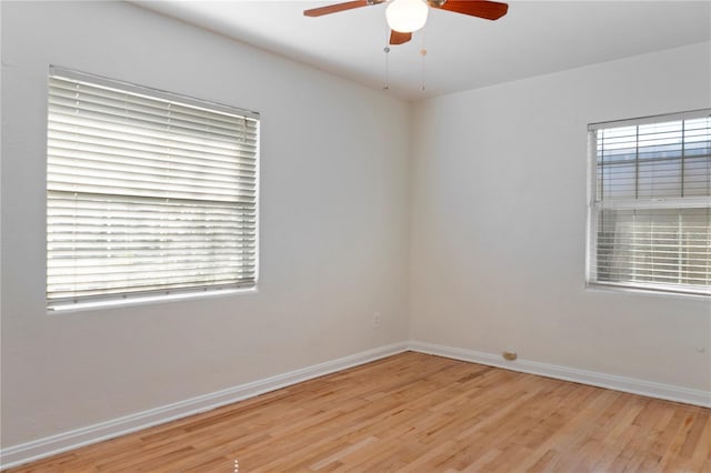 spare room featuring a ceiling fan, light wood-style floors, and baseboards