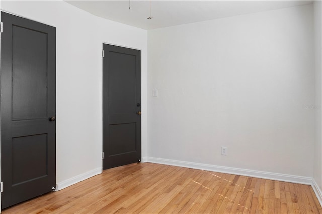 unfurnished room with baseboards and light wood finished floors