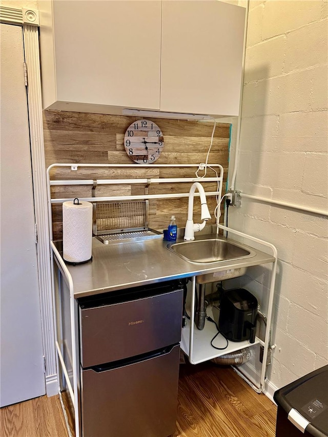 details with a sink, wood finished floors, and concrete block wall