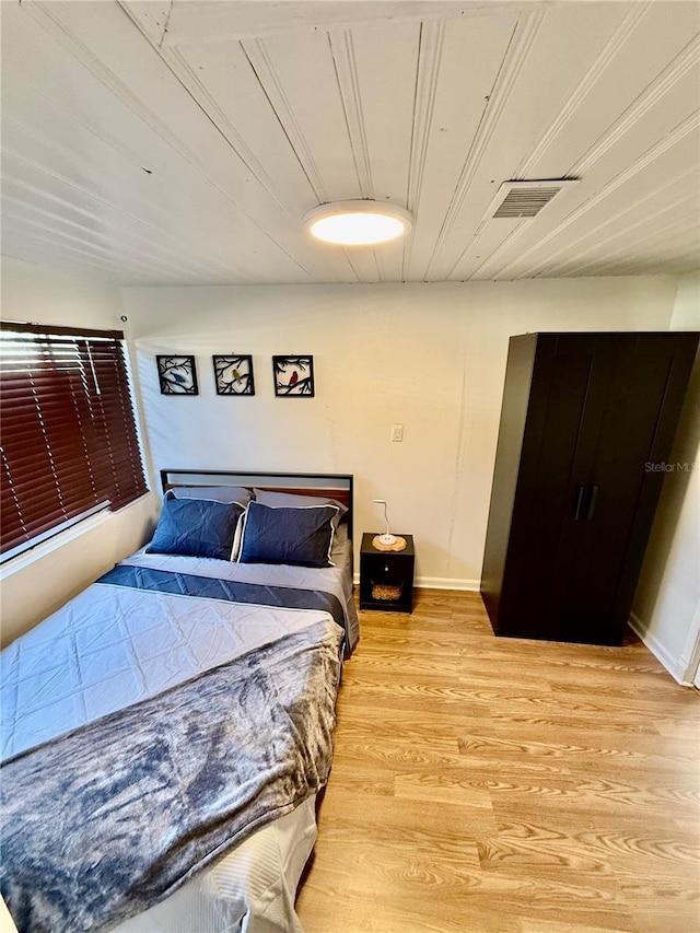 bedroom with visible vents, baseboards, light wood-style flooring, and wooden ceiling