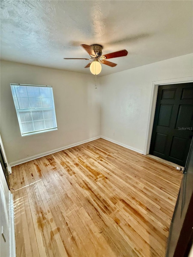 empty room with light wood-type flooring, baseboards, a textured ceiling, and a ceiling fan