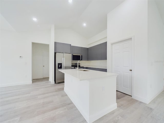 kitchen featuring a sink, light countertops, appliances with stainless steel finishes, light wood-style floors, and a kitchen island with sink