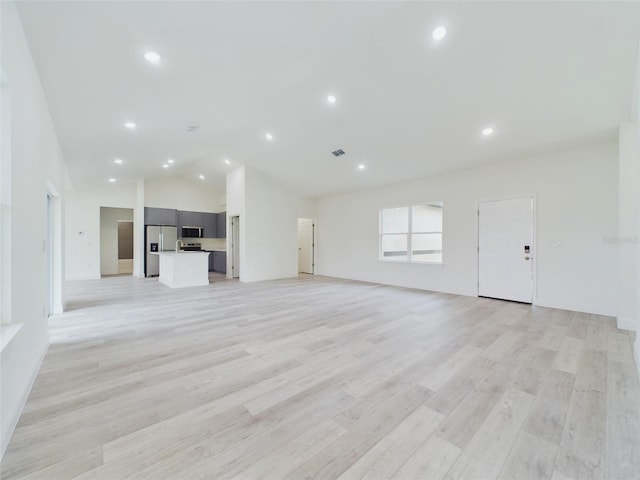 unfurnished living room with recessed lighting, light wood-style flooring, high vaulted ceiling, and visible vents