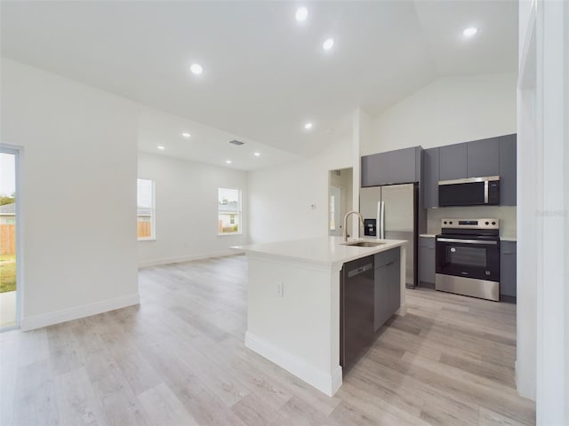 kitchen with light wood finished floors, a sink, light countertops, appliances with stainless steel finishes, and modern cabinets