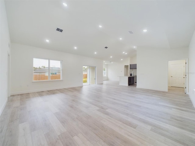 unfurnished living room featuring recessed lighting, visible vents, lofted ceiling, and light wood-style floors