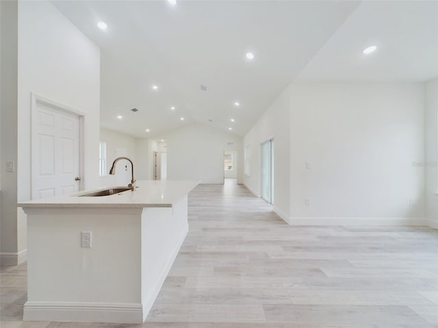 kitchen featuring light wood finished floors, open floor plan, an island with sink, lofted ceiling, and a sink