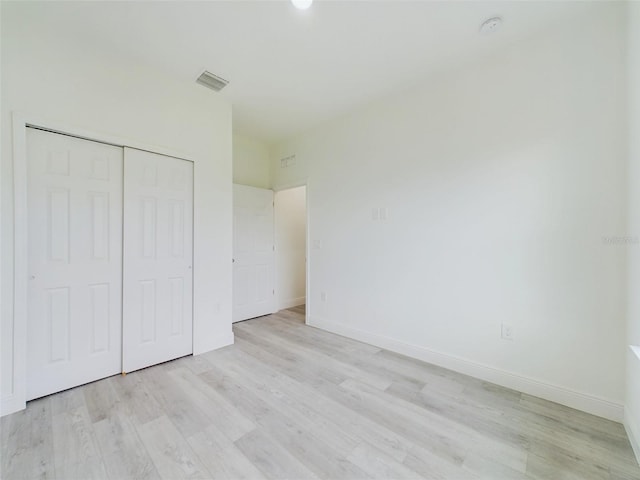 unfurnished bedroom with visible vents, baseboards, light wood-style floors, and a closet