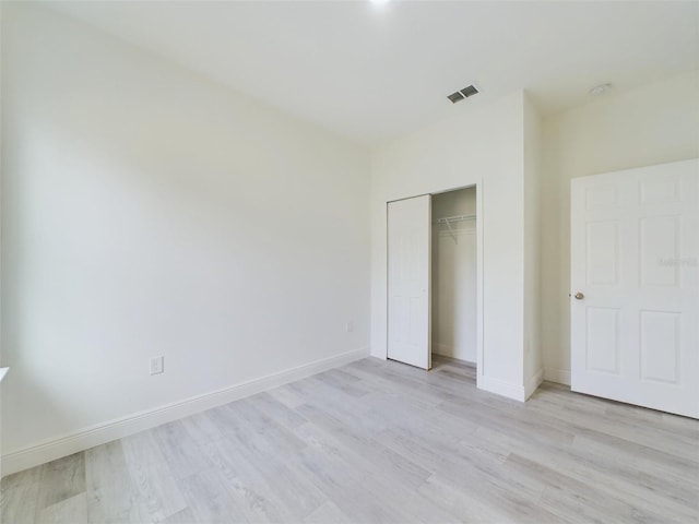 unfurnished bedroom with visible vents, baseboards, a closet, and light wood finished floors