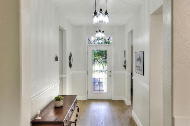 foyer entrance featuring a notable chandelier, baseboards, and light wood-style floors