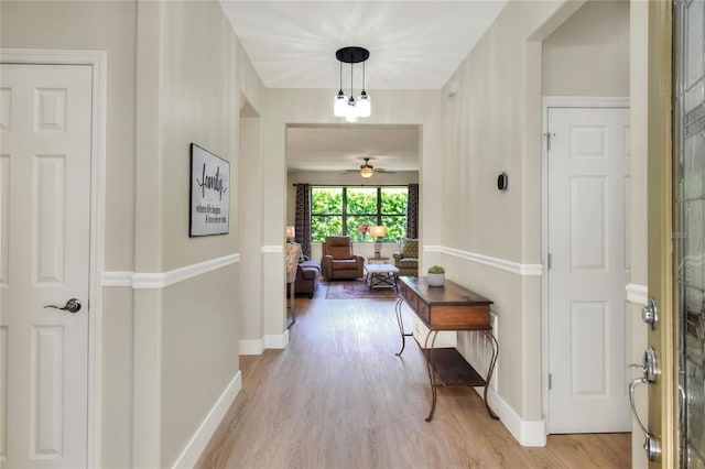 hall featuring light wood-type flooring and baseboards