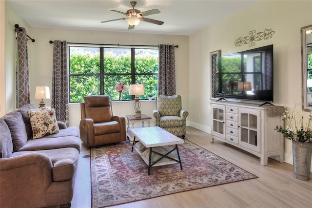 living room featuring light wood-style floors, baseboards, and ceiling fan