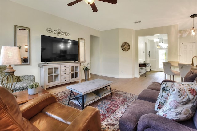 living area featuring a ceiling fan, wood finished floors, visible vents, and baseboards