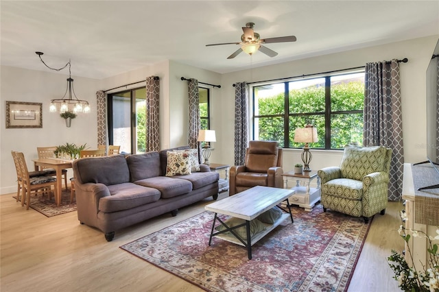 living area featuring ceiling fan with notable chandelier and light wood-type flooring