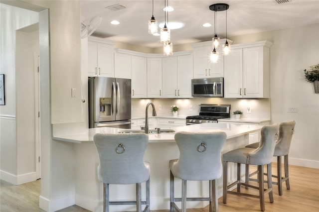 kitchen featuring visible vents, a sink, white cabinetry, appliances with stainless steel finishes, and light countertops