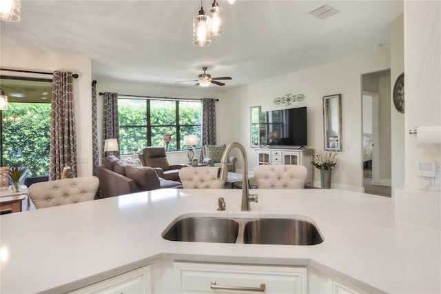 kitchen featuring visible vents, a sink, open floor plan, white cabinetry, and light countertops