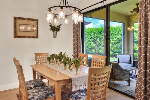 dining room with baseboards, wood finished floors, and ceiling fan with notable chandelier