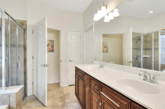 bathroom featuring double vanity, a stall shower, tile patterned floors, and a sink