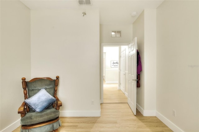 corridor with visible vents, light wood-type flooring, and baseboards