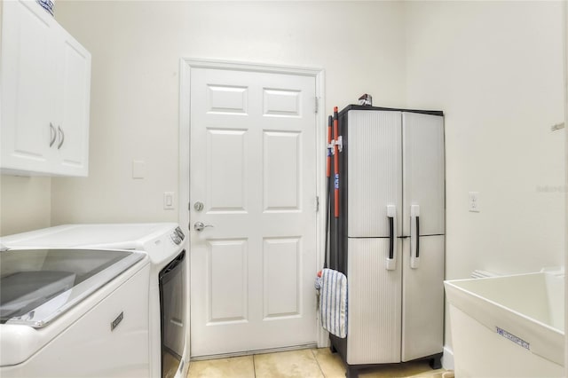 clothes washing area featuring light tile patterned flooring, cabinet space, and washing machine and clothes dryer