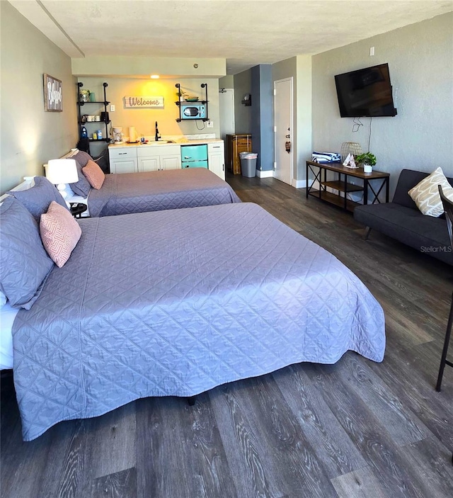 bedroom with dark wood finished floors, baseboards, and a sink