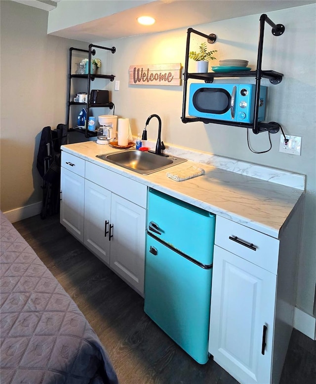 kitchen with a sink, recessed lighting, white cabinets, light countertops, and dark wood-style flooring