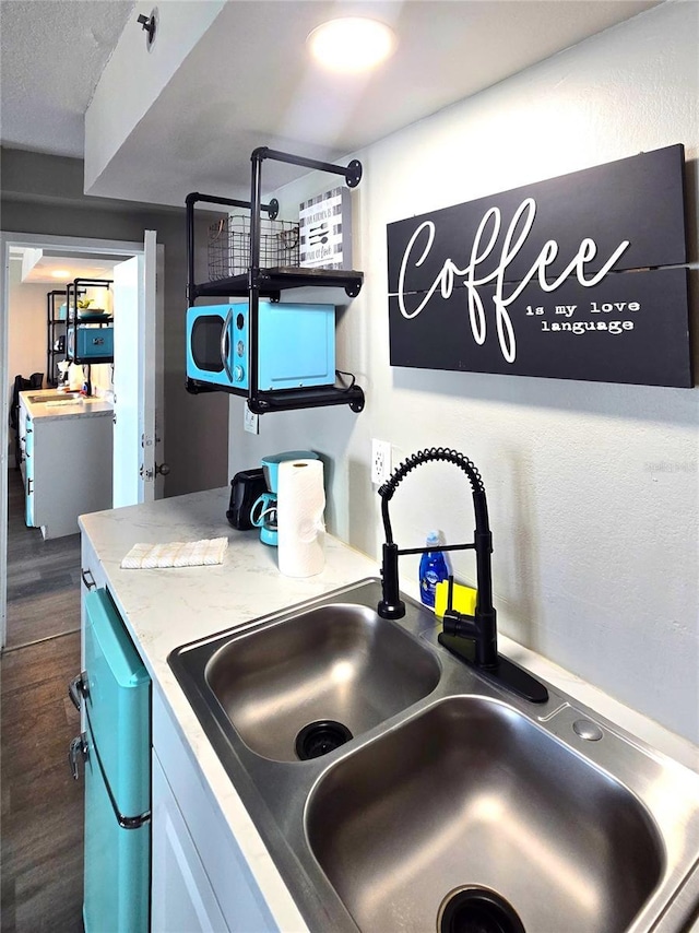 kitchen featuring a sink, dishwashing machine, dark wood finished floors, and light countertops