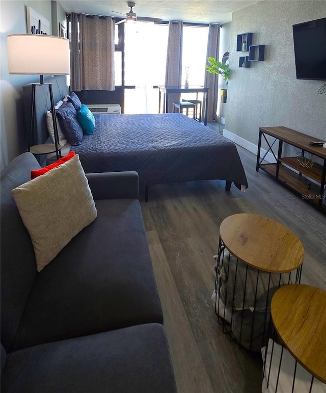 bedroom with baseboards, wood finished floors, and a textured wall