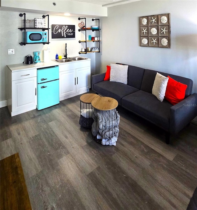 living area with wet bar, dark wood-type flooring, and baseboards