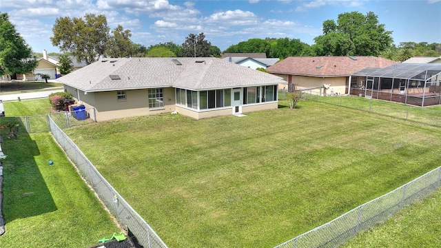 rear view of house featuring a yard, stucco siding, a fenced backyard, and a sunroom